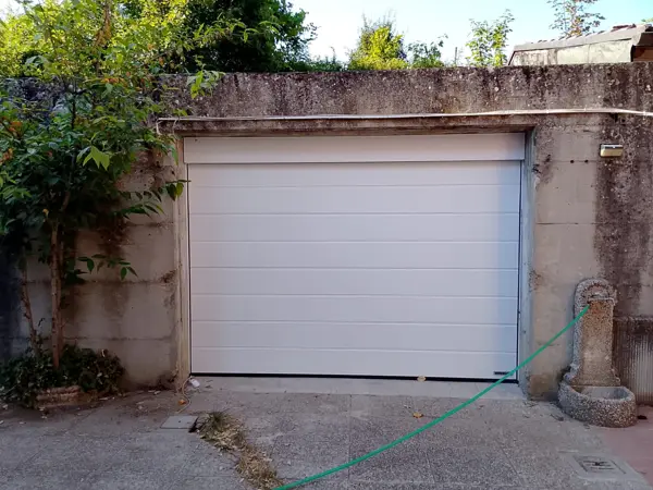 Porta sezionale bianca in muro di pietra