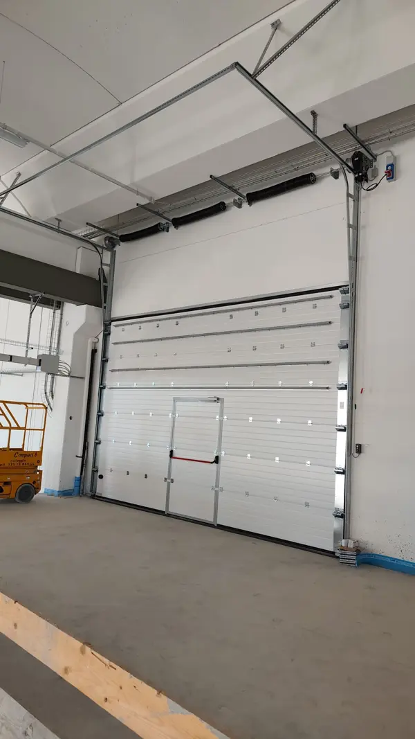 Portone sezionale industriale con porta pedonale